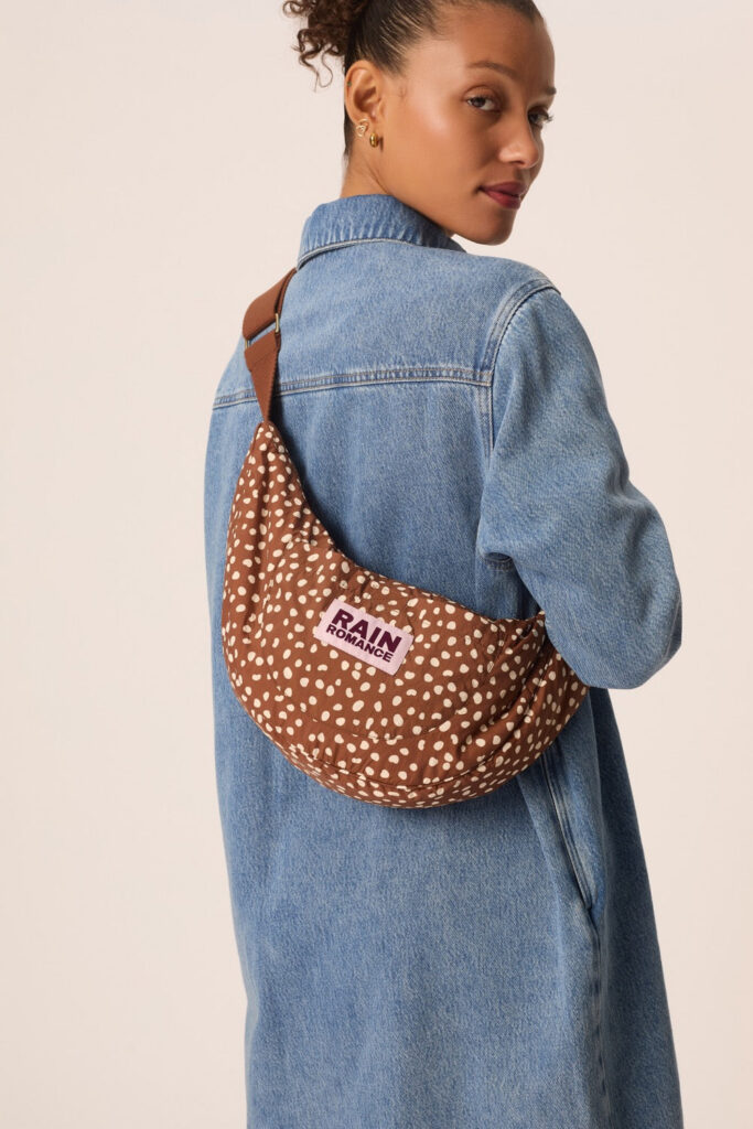 Sac banane Bambiche de Des Petits Hauts, imprime faon ecru sur fond marron, porte en bandouliere sur une veste en jean