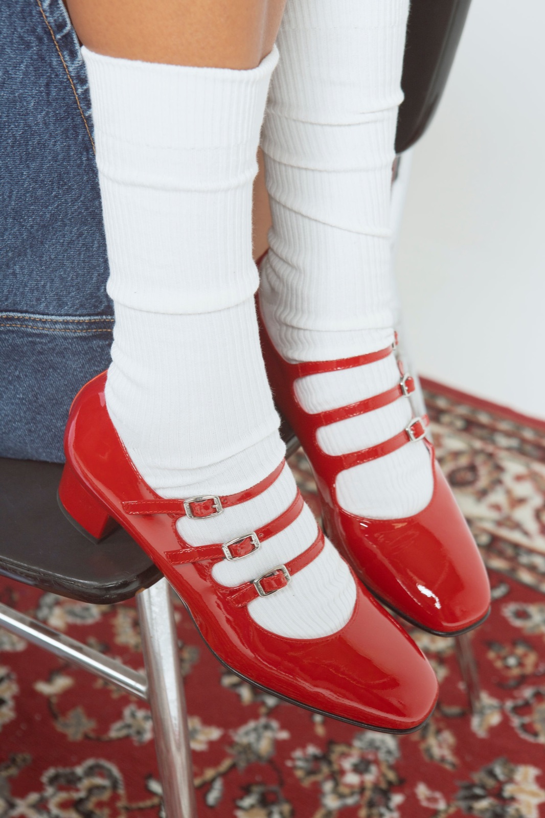 Babies Kina de Carel en cuir verni rouge à trois brides, portées avec des chaussettes blanches