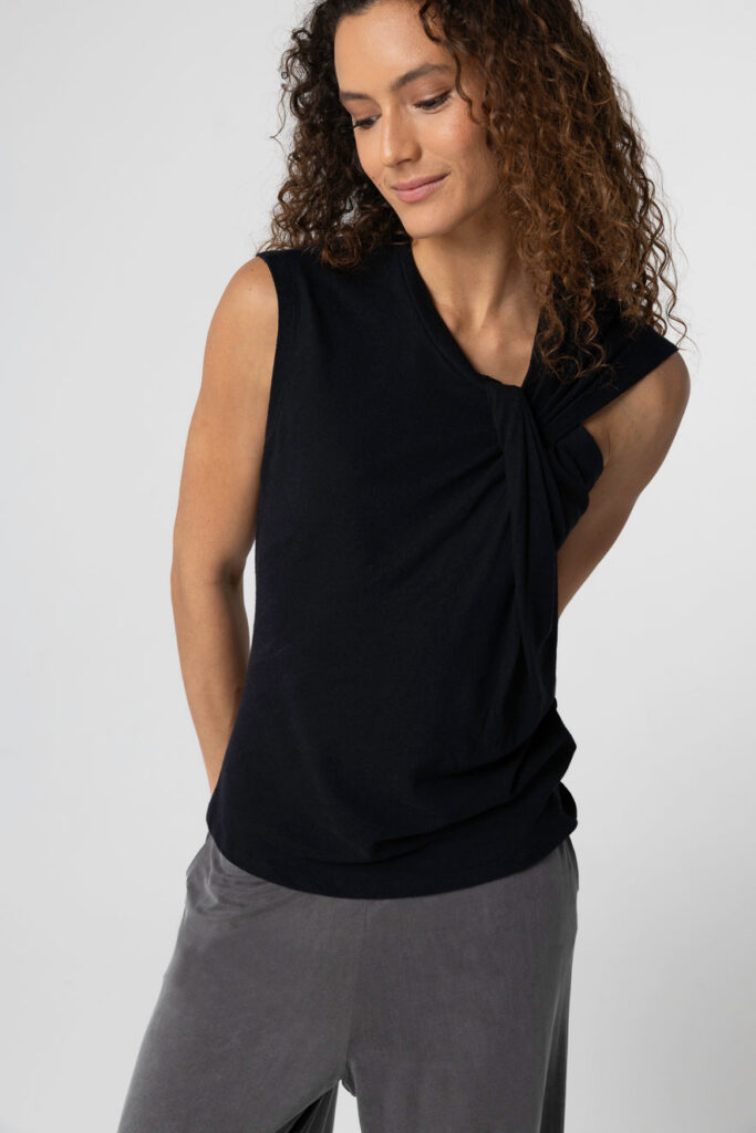 Débardeur noir sans manches à col noué en coton et lin de Majestic Filatures, porté avec un pantalon gris