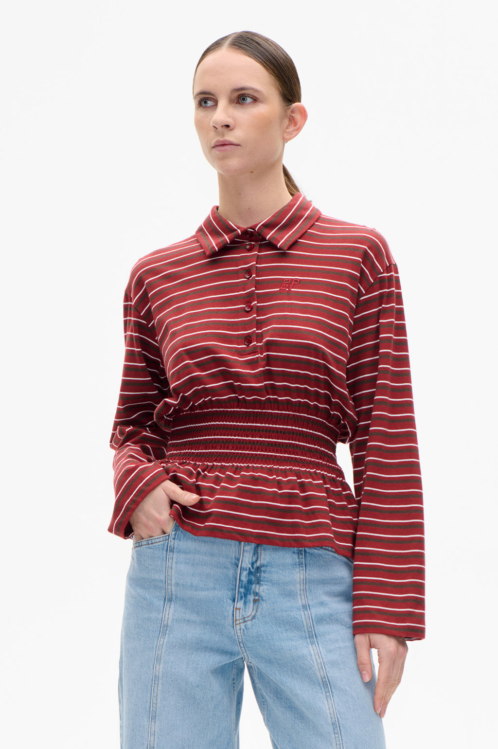Blouse Josefin de Baum und Pferdgarten en rayures rouge Syrah, col pointu boutonné et taille smockée, portée avec un jean