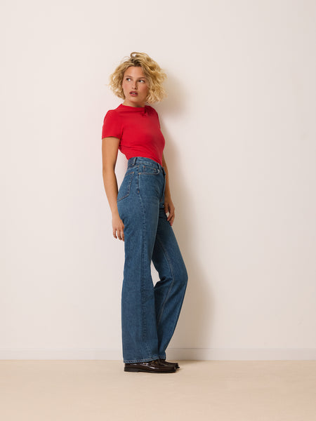 Jean Madeleine de Rouje, taille haute et jambe évasée en denim indigo, porté avec un tee-shirt rouge