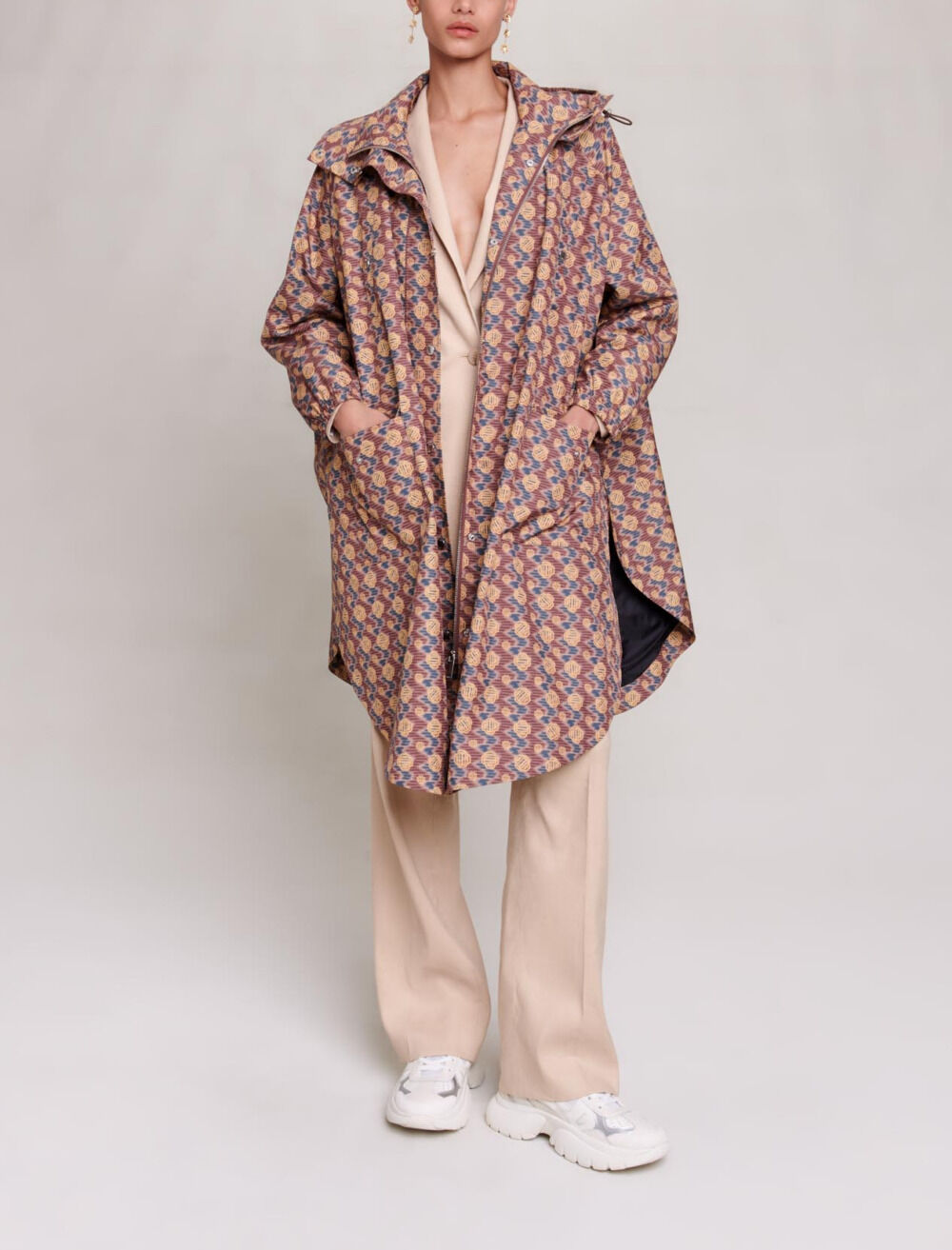 Manteau monogramme Maje, cape coupe-vent oversize à imprimé all-over moutarde, rose et bleu, portée avec un pantalon fluide écru