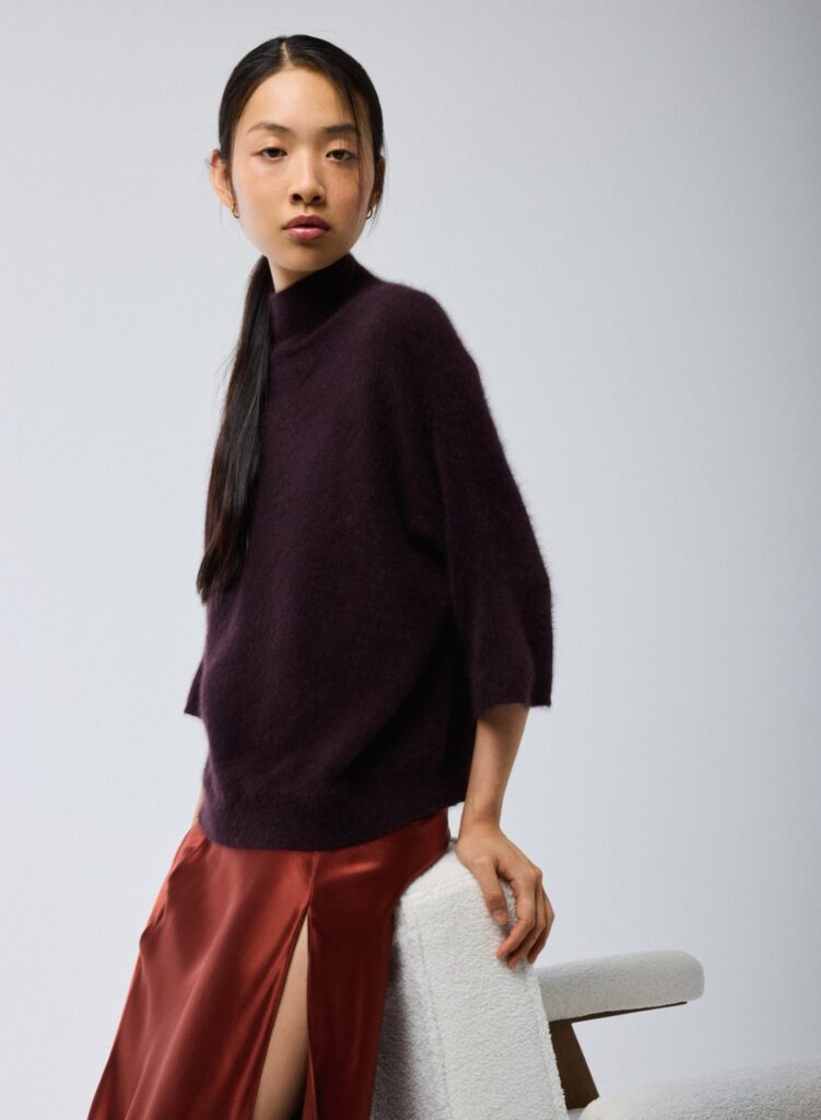 Pull aubergine col roulé à manches kimono en laine raccoon de Majestic Filatures, porté avec une jupe en satin rouille