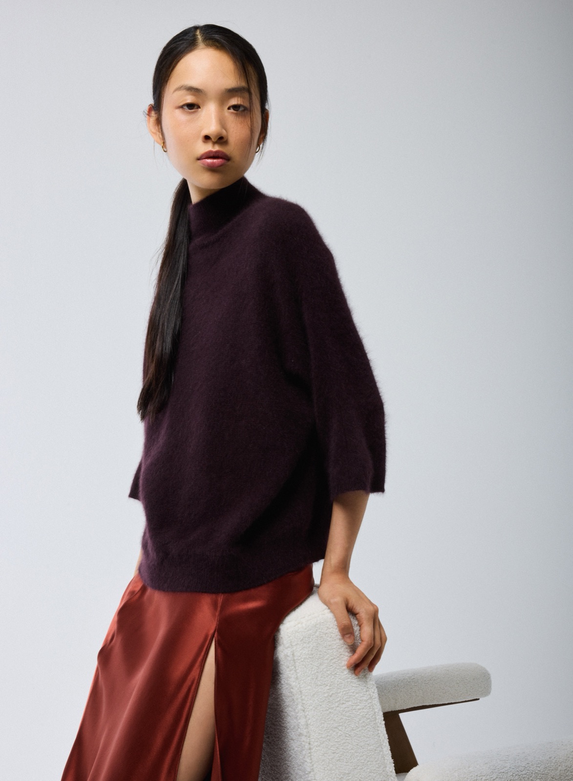 Pull aubergine col roulé à manches kimono en laine raccoon de Majestic Filatures, porté avec une jupe en satin rouille