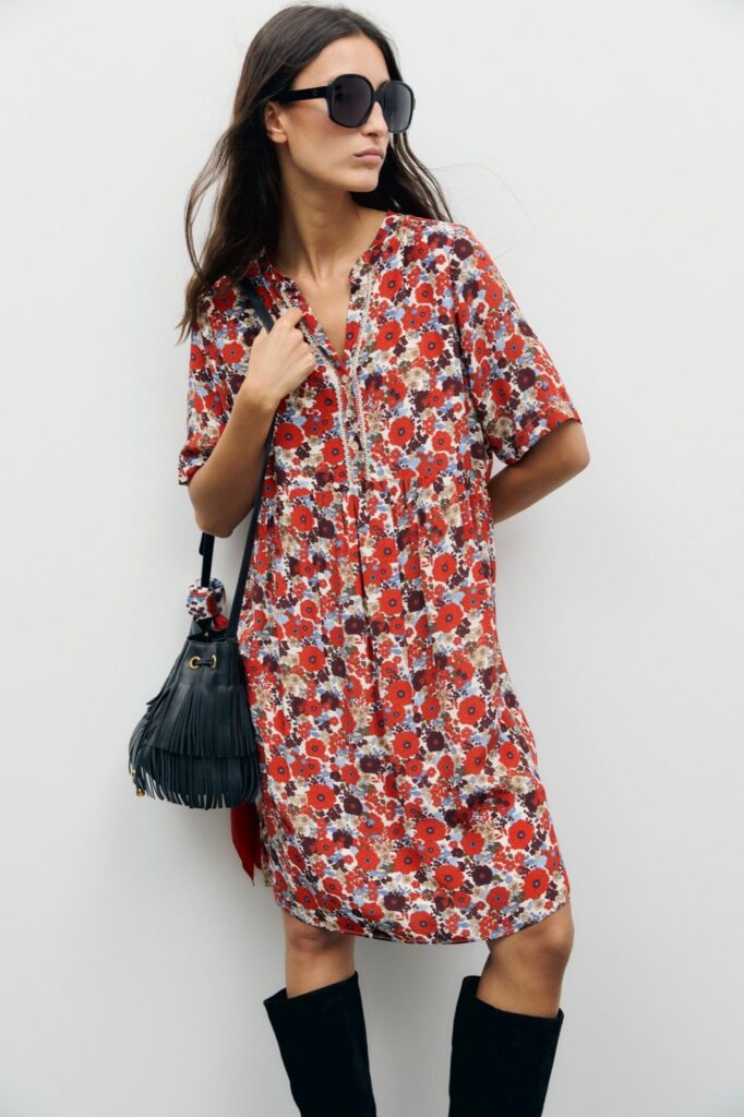 Robe courte fleurie Colle de Gérard Darel, imprimé floral rouge et bordeaux, portée avec des bottes hautes noires