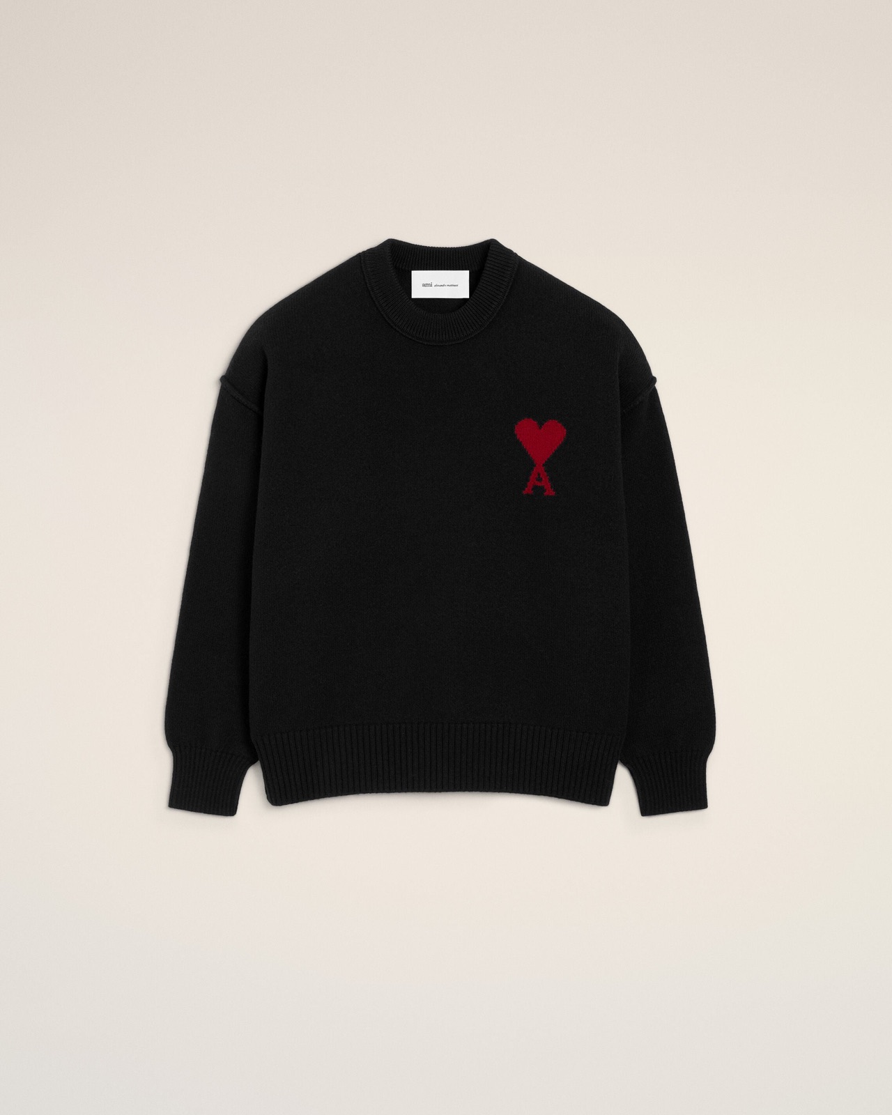Pull col rond en laine merinos noire d'Ami Paris avec le logo Ami de Coeur rouge tricote en intarsia sur la poitrine