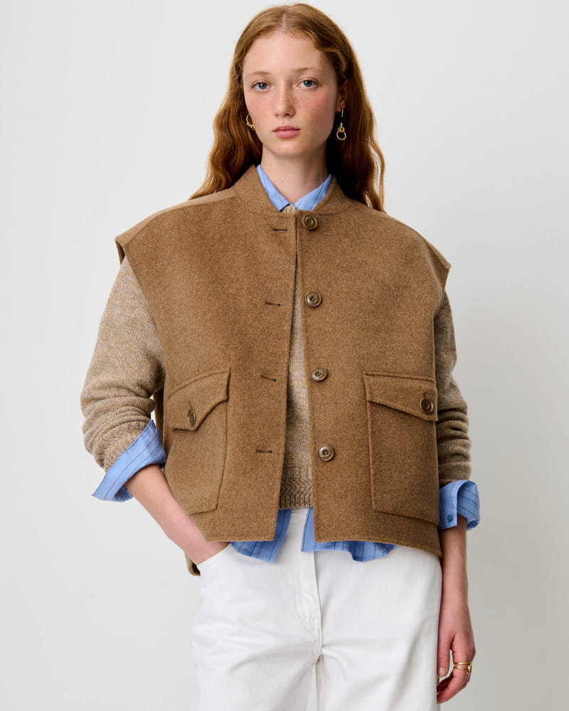Gilet sans manches Parkless de Sessùn en laine fauve, porté sur un pull en maille et une chemise rayée bleue