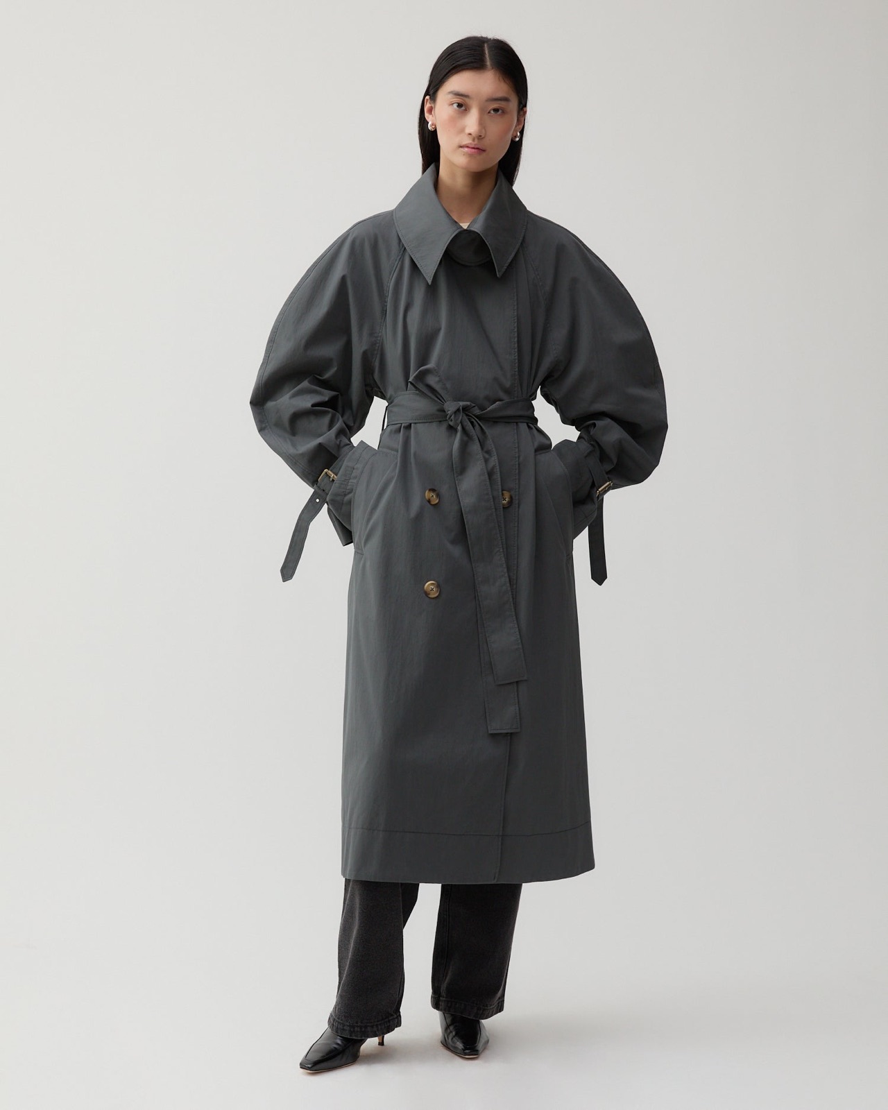 Trench Romy de Rejina Pyo en coton gris ardoise, coupe croisée oversize, grand col, manches rondes et large ceinture nouée à la taille