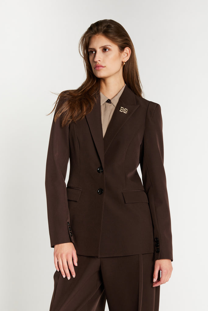 Femme portant le blazer Sora de Bruuns Bazaar en brun foncé, taille marquée, col cranté et broche BB dorée