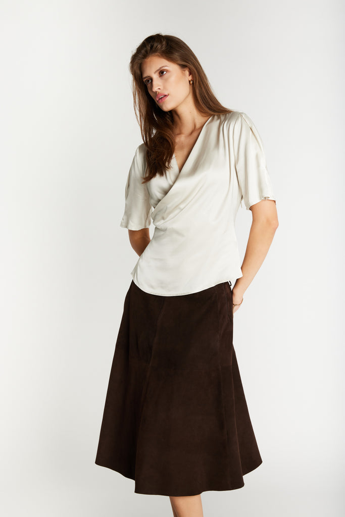 Jupe Sueda en daim brun de Bruuns Bazaar, taille haute et coupe évasée longueur genou, portée avec un top satin crème