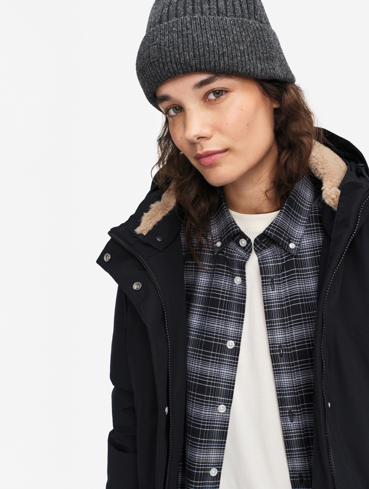 Parka GORE-TEX mi-longue ajustée noire Aigle, col doublé de fourrure, portée sur une chemise à carreaux