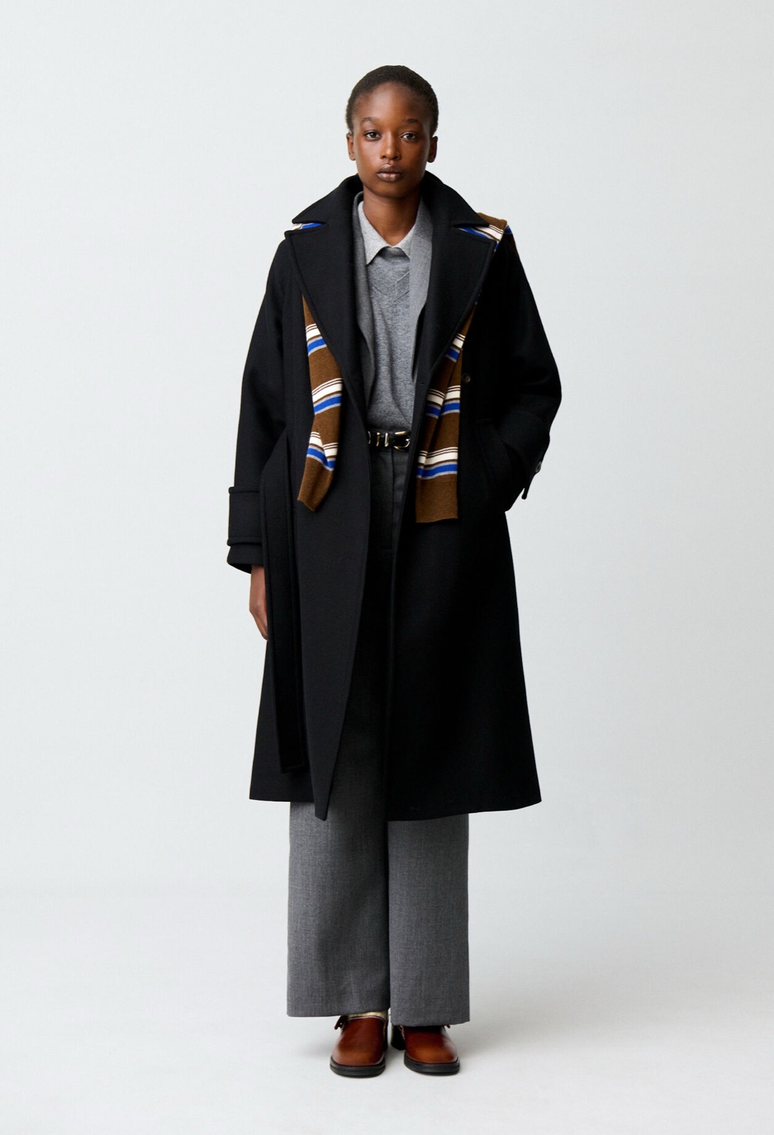 Long manteau noir en laine mélangée à col tailleur et ceinture, porté sur un pantalon gris, Claudie Pierlot
