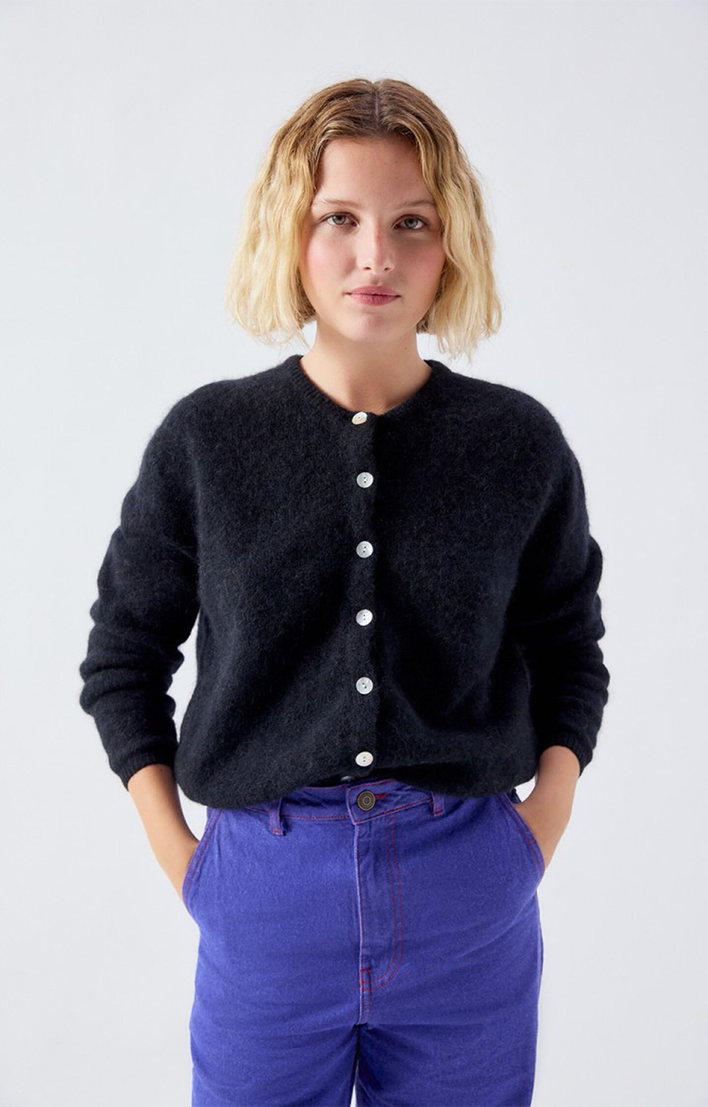 Gilet Vitow noir en maille alpaga d'American Vintage, coupe boule et boutons de nacre, porté sur un pantalon bleu électrique