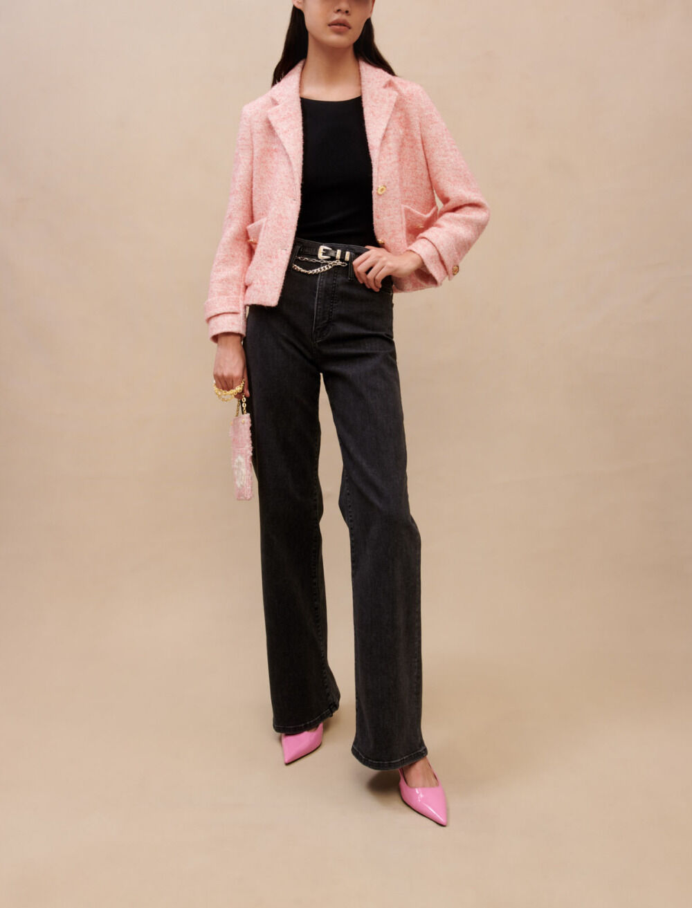 Veste de tailleur courte en effet tweed rose poudré Maje, portée sur un top noir et un jean large