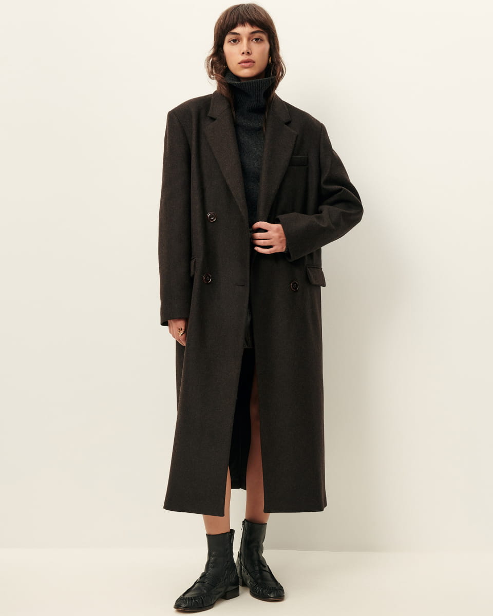 Manteau Nara de Sessùn en drap de laine brun teck, coupe droite longue à double boutonnage, porté sur maille foncée et bottines noires