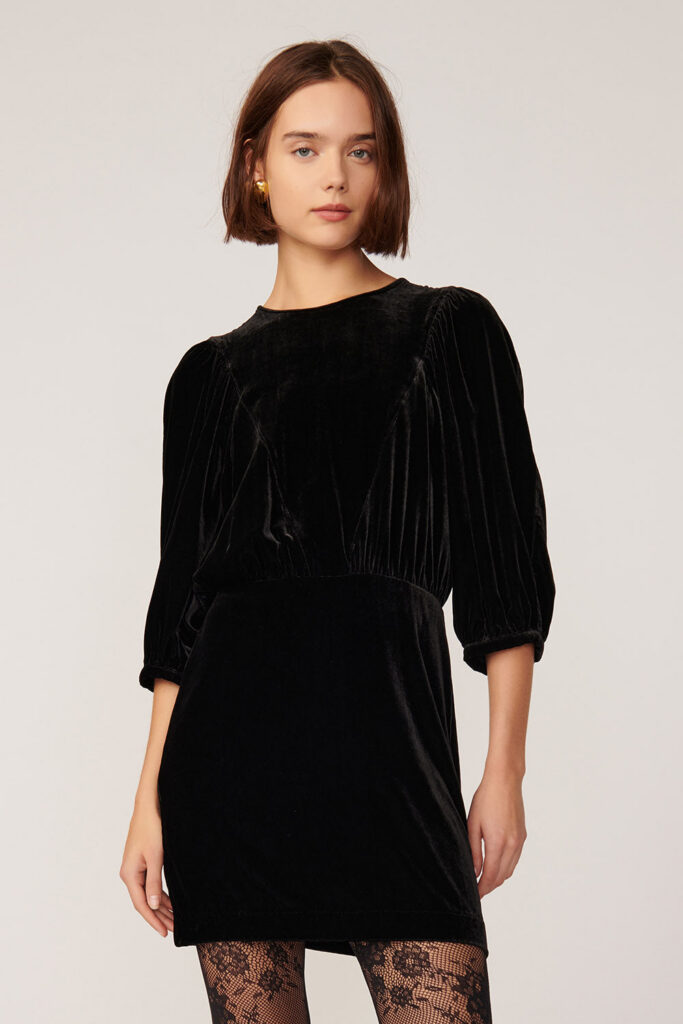 Robe courte en panne de velours noire Landria de Des Petits Hauts, manches ballon mi-longues et col rond, portee avec des collants en dentelle
